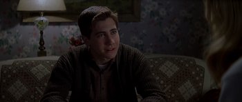 Movie still from “October Sky” (1999), directed by Joe Johnston – A man sitting on top of a couch in front of a window; Close Up shot, Over the shoulder angle