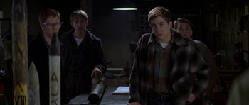 Movie still from “October Sky” (1999), directed by Joe Johnston – Two young men standing next to each other in front of a table; Medium shot, Over the shoulder angle