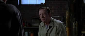 Movie still from “October Sky” (1999), directed by Joe Johnston – A man in a tan shirt is sitting in a room; Close Up shot, Over the shoulder angle