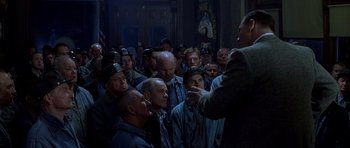 Movie still from “October Sky” (1999), directed by Joe Johnston – A group of men standing in front of each other in a room; Medium shot, High angle