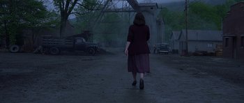 Movie still from “October Sky” (1999), directed by Joe Johnston – A woman walking down a street in the rain; Wide shot, Over the shoulder angle