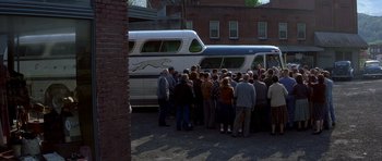 Movie still from “October Sky” (1999), directed by Joe Johnston – A group of people standing in front of a parked bus; Extreme Wide shot, High angle