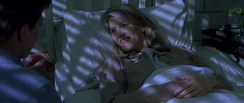 Movie still from “October Sky” (1999), directed by Joe Johnston – A woman is laying in a bed with a smile on her face; Medium shot, High angle
