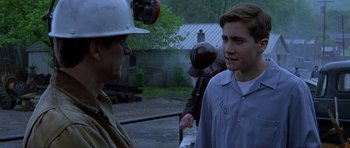 Movie still from “October Sky” (1999), directed by Joe Johnston – A man in a hard hat talking to another man in a blue shirt; Medium shot, Over the shoulder angle