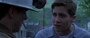 Movie still from “October Sky” (1999), directed by Joe Johnston – A young man looking at another man with a helmet on; Close Up shot, Over the shoulder angle