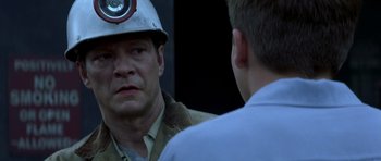 Movie still from “October Sky” (1999), directed by Joe Johnston – A man wearing a hard hat talking to another man in front of a building; Close Up shot, Over the shoulder angle