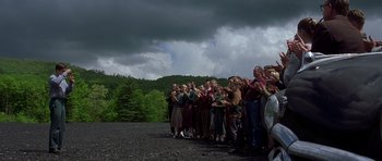 Movie still from “October Sky” (1999), directed by Joe Johnston – A group of people standing on top of a dirt field; Extreme Wide shot, Over the shoulder angle