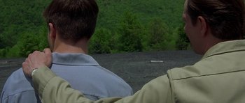 Movie still from “October Sky” (1999), directed by Joe Johnston – Two men looking out over a field with trees in the background; Close Up shot, Over the shoulder angle