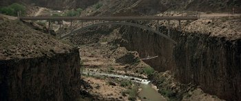 Movie still from “Octopussy” (1983), directed by John Glen – An airplane is flying over a bridge over a river; Extreme Wide shot, High angle