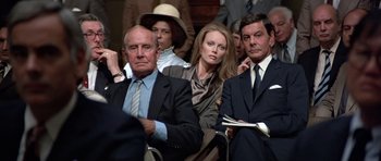 Movie still from “Octopussy” (1983), directed by John Glen – A group of people sitting next to each other in a room; Medium shot, Over the shoulder angle