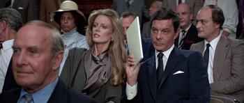 Movie still from “Octopussy” (1983), directed by John Glen – A man and a woman holding a laptop in front of a group of people; Close Up shot, Over the shoulder angle