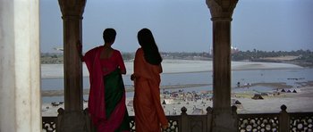 Movie still from “Octopussy” (1983), directed by John Glen – Two women in sarees looking out over a beach; Wide shot, High angle