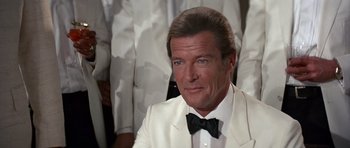 Movie still from “Octopussy” (1983), directed by John Glen – Roger moore as james bond wearing a white tuxedo; Close Up shot, Over the shoulder angle