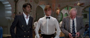 Movie still from “Octopussy” (1983), directed by John Glen – A group of men standing next to each other in a room; Medium shot, Low angle