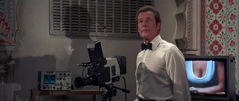 Movie still from “Octopussy” (1983), directed by John Glen – A man standing in front of a video camera; Medium shot, Low angle