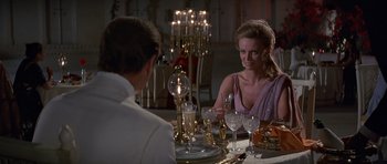 Movie still from “Octopussy” (1983), directed by John Glen – A man and a woman sitting at a dinner table; Medium shot, Over the shoulder angle