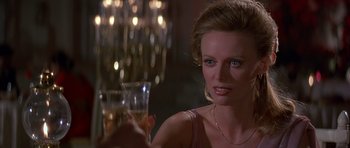 Movie still from “Octopussy” (1983), directed by John Glen – A woman sitting at a table with a glass of wine; Close Up shot, Over the shoulder angle