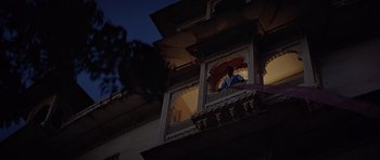 Movie still from “Octopussy” (1983), directed by John Glen – A person standing on a balcony looking out at the night sky; Wide shot, Low angle