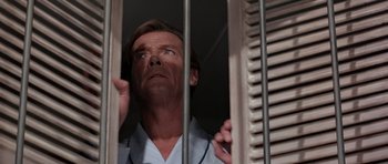 Movie still from “Octopussy” (1983), directed by John Glen – A man in pajamas standing behind a metal cage; Close Up shot, Low angle