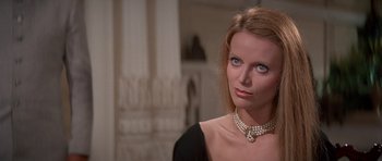 Movie still from “Octopussy” (1983), directed by John Glen – A woman wearing a pearl necklace and a black dress; Close Up shot, Over the shoulder angle
