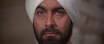 Movie still from “Octopussy” (1983), directed by John Glen – A man with a beard wearing a white turban; Close Up shot, High angle