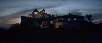 Movie still from “Octopussy” (1983), directed by John Glen – A large castle with lights on the top of it; Extreme Wide shot, Low angle