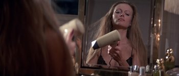 Movie still from “Octopussy” (1983), directed by John Glen – A woman blow drying her hair in front of a mirror; Close Up shot, Low angle