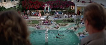 Movie still from “Octopussy” (1983), directed by John Glen – People are swimming in a pool surrounded by flowers; Extreme Wide shot, High angle