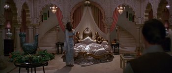 Movie still from “Octopussy” (1983), directed by John Glen – A woman standing in front of an ornate bed; Wide shot, High angle