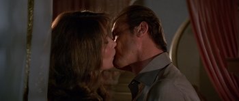 Movie still from “Octopussy” (1983), directed by John Glen – A man and a woman kissing each other in front of a wall; Close Up shot, Low angle