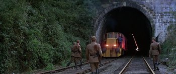 Movie still from “Octopussy” (1983), directed by John Glen – Two men in uniform walking on train tracks next to a tunnel; Wide shot, Low angle