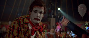Movie still from “Octopussy” (1983), directed by John Glen – A man in a clown suit and a red bow tie; Close Up shot, Low angle