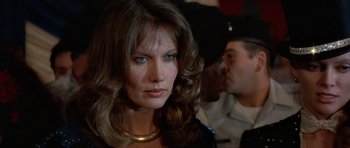 Movie still from “Octopussy” (1983), directed by John Glen – A person wearing a necklace; Close Up shot, Over the shoulder angle