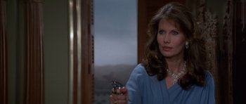 Movie still from “Octopussy” (1983), directed by John Glen – A woman holding a cell phone while wearing a blue shirt; Close Up shot, Over the shoulder angle