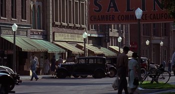 Movie still from “Of Mice and Men” (1992), directed by Gary Sinise – An antique car is parked on the side of the street; Extreme Wide shot, High angle