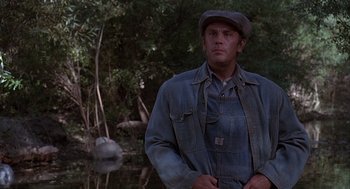 Movie still from “Of Mice and Men” (1992), directed by Gary Sinise – A man standing next to a body of water; Medium shot, Over the shoulder angle