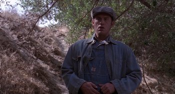Movie still from “Of Mice and Men” (1992), directed by Gary Sinise – A man wearing a hat and overalls standing in front of a tree; Close Up shot, Low angle