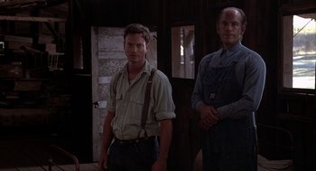Movie still from “Of Mice and Men” (1992), directed by Gary Sinise – Two men standing next to each other in a room; Medium shot, Low angle