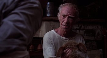 Movie still from “Of Mice and Men” (1992), directed by Gary Sinise – An older man holding a dog in his hands; Close Up shot, Over the shoulder angle