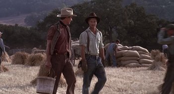 Movie still from “Of Mice and Men” (1992), directed by Gary Sinise – A couple of men walking across a field; Wide shot, Low angle