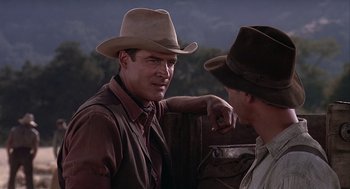 Movie still from “Of Mice and Men” (1992), directed by Gary Sinise – A man in a cowboy hat talking to another man; Close Up shot, Over the shoulder angle