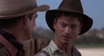 Movie still from “Of Mice and Men” (1992), directed by Gary Sinise – A man in a cowboy hat is looking at the camera; Close Up shot, Over the shoulder angle