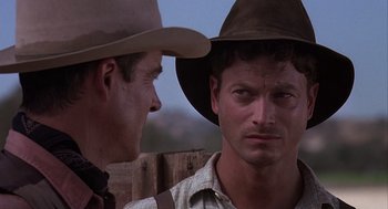 Movie still from “Of Mice and Men” (1992), directed by Gary Sinise – A man in a cowboy hat is talking to another man; Close Up shot, Over the shoulder angle
