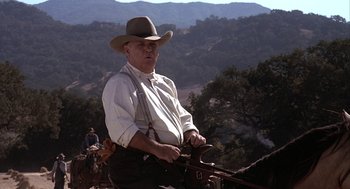 Movie still from “Of Mice and Men” (1992), directed by Gary Sinise – An older man in a cowboy hat riding on a horse; Medium shot, Low angle