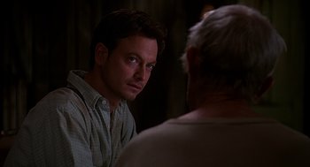 Movie still from “Of Mice and Men” (1992), directed by Gary Sinise – A man looking at another man in a room; Close Up shot, Over the shoulder angle