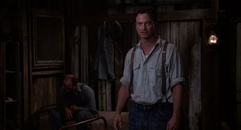 Movie still from “Of Mice and Men” (1992), directed by Gary Sinise – A man standing next to another man in a room; Medium shot, Over the shoulder angle