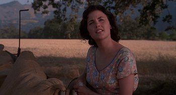 Movie still from “Of Mice and Men” (1992), directed by Gary Sinise – A woman sitting in a field with her eyes wide open; Close Up shot, Over the shoulder angle