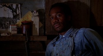 Movie still from “Of Mice and Men” (1992), directed by Gary Sinise – A man wearing a blue shirt and a blue jean shirt; Close Up shot, Low angle