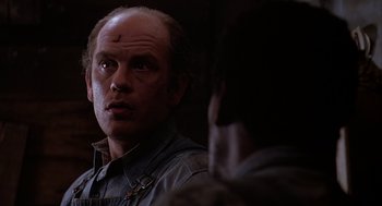 Movie still from “Of Mice and Men” (1992), directed by Gary Sinise – A man looking into the distance with a cross on his forehead; Close Up shot, Over the shoulder angle