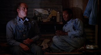 Movie still from “Of Mice and Men” (1992), directed by Gary Sinise – A couple of men sitting next to each other in a room; Medium shot, Low angle